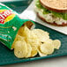 A sandwich on a plate next to a bag of Lay's Sour Cream & Onion Potato Chips.