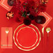 A red and gold table setting with Sophistiplate Scarlet wavy paper dinner plates and gold napkins.