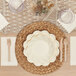 A table setting with a white plate, Sophistiplate Cream Scalloped Edge Paper Guest Towel, and a knife.