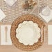 A table setting with a white plate and Sophistiplate ECO Cream Birchwood Cutlery on a woven mat.