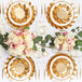 A table set with white and gold Sophistiplate wavy paper dinner plates and flowers.