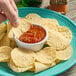 A hand dipping a Tostitos Bite Size Round tortilla chip into a bowl of salsa.