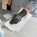 A person wearing black gloves cleaning a counter with a white WypAll L30 wiper.