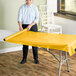 A woman rolling a yellow plastic sheet on a table.