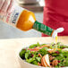 A person pouring Ken's Golden Italian Dressing onto a salad.