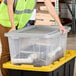 A woman in a safety vest opening a clear plastic Tough Box storage tote.