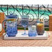 A tray of Sophistiplate cobalt blue plastic wine glasses with ice and a lemon in one of the glasses.