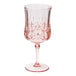 A close-up of a Sophistiplate blush pink plastic wine glass.
