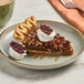 A slice of pecan pie with whipped cream and a pecan on a plate.