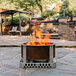 A BREEO Corten steel fire pit with flames in it on a stone patio.