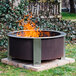A BREEO Corten steel fire pit in a yard with flames.