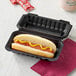 A hot dog in a Ecopax black plastic hinged container.