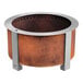 A round metal BREEO Corten steel fire pit on a table in an outdoor patio.