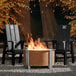 Two chairs next to a BREEO Corten Steel fire pit on a patio.