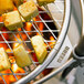 A BREEO stainless steel grill grate with food on skewers cooking over a fire.