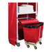 A red laundry cart with two shelves and a red cover with a roll of towels.