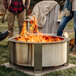 A BREEO stainless steel smokeless fire pit with people standing around it on a patio.