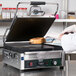 A person in a white coat using a Waring panini grill to make a sandwich.