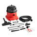 A red and black NaceCare Solutions canister vacuum with accessories on a table.