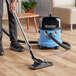 A person using a NaceCare wet/dry vacuum to clean a hardwood floor.