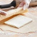 A person rolling out Stratas Buckeye Z Puff Pastry and Danish Margarine Shortening with a rolling pin.