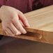 A person's hand holding a Choice wood cutting board