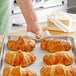 A hand preparing a croissant on a tray.