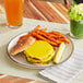 A cheeseburger with Rind Veggie Underground Carrot cheese slices and fries on a plate.