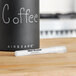 A white Planetary Design Airscape coffee mug with white text on the table next to a white marker.