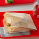 A sandwich in a Bagcraft EcoCraft paper bag on a red tray with a can.