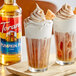 Two glasses of ice cream with whipped cream and a bottle of Torani Pumpkin Pie Flavoring Syrup.