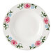 A white Tuxton china pasta bowl with pink flowers and green leaves on it.