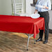 A woman standing at a table with a red Table Mate plastic table cover.