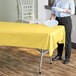 A yellow plastic Table Mate tablecloth on a table with white plates.