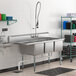 A Regency stainless steel three compartment sink with a left drainboard.