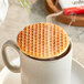 An Individually wrapped Vafels vegan maple stroopwafel on a cup of coffee.