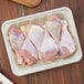 A World Centric compostable fiber meat tray with raw chicken legs on it.