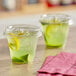 Two Choice clear plastic cups with lemonade and lime slices on a counter.