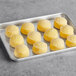 A white Toque tray with round yellow cheese bites.