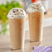 Two Choice plastic cups of iced coffee with whipped cream and chocolate chips.