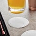 A glass of beer over a white round Hoffmaster linen-like coaster.