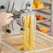 A person using an Estella spaghetti pasta die to cut noodles.