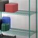 A Regency green epoxy wire shelf with plastic containers on it.