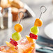 Fruit on Choice stainless steel skewers in a glass of liquid.
