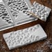 A white rectangular Pavoni chocolate bar mold with a pattern on it.