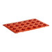 A red silicone Pavoni round baking mold with 24 compartments.