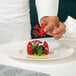 A hand using a Pavoni Gourmand coral silicone baking mold to make red flower-shaped candy.