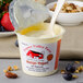 A plastic container of Pequea Valley Farm Amish-Made mango yogurt with a spoonful of fruit.