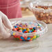A person holding an Inline Plastics Safe-T-Fresh plastic container filled with colorful candy.