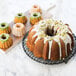 A close-up of a Nordic Ware Bundt cake with white frosting and pistachios.